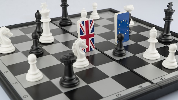 Pezzi degli scacchi e bandiere dell'Unione europea e della Gran Bretagna su una scacchiera Gioco politico