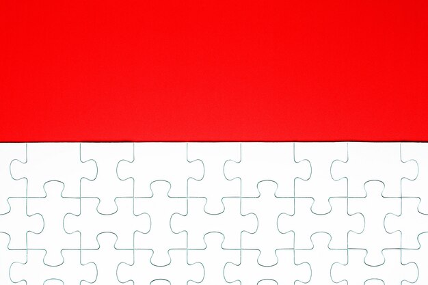 Pezzi del puzzle bianco su uno sfondo rosso separato