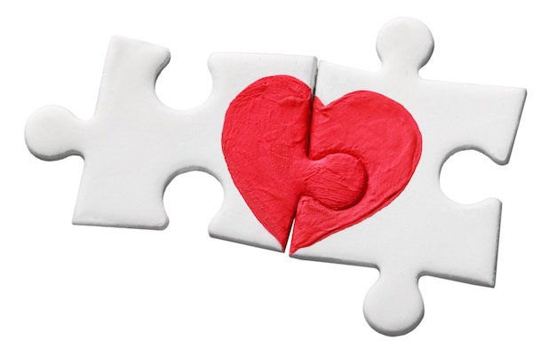 Pezzi del puzzle con cuore rosso dipinto isolato su sfondo bianco