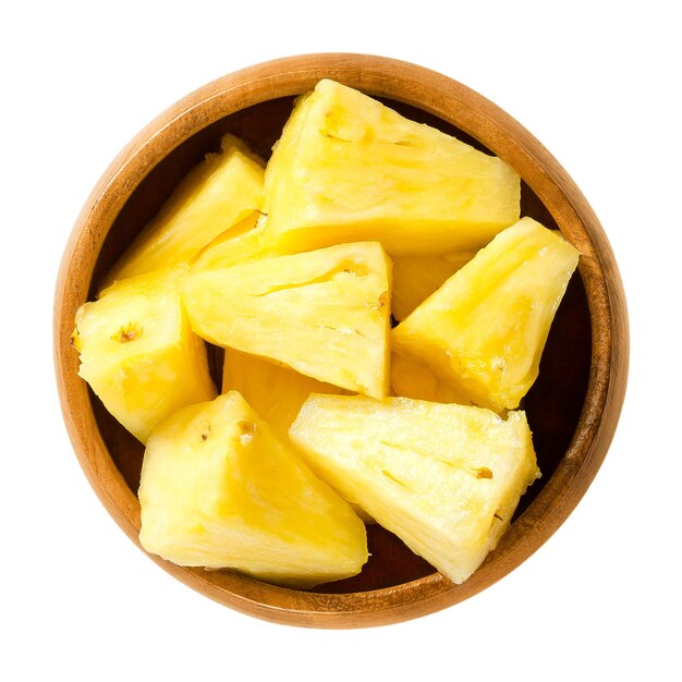 Pezzi di ananas in ciotola di legno sopra bianco