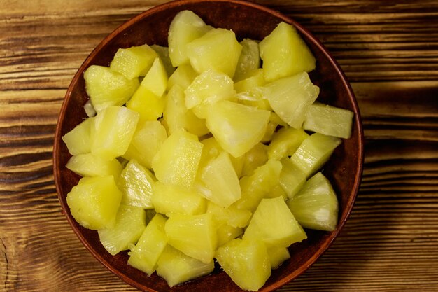 Pezzi di ananas in scatola in piatto di ceramica su tavola di legno