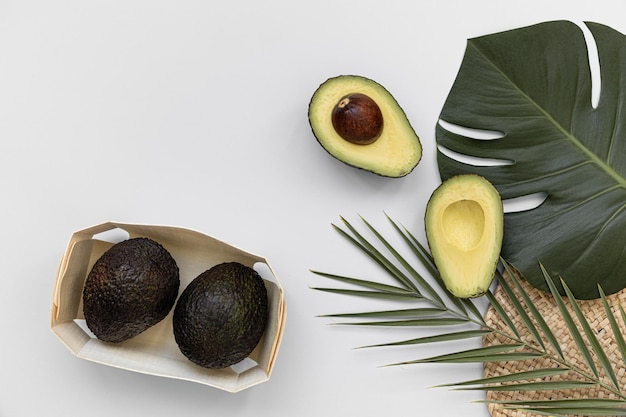 Pezzi di avocado su un pavimento di fibre naturali e ha uno sfondo di natura Foglia di monstera tropicale