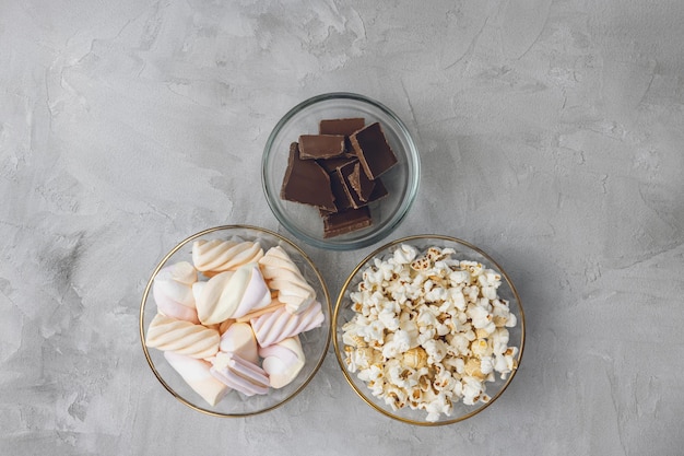 Pezzi di barretta di cioccolato marshmallow popcorn in ciotole Ingredienti per cucinare lo spazio della copia