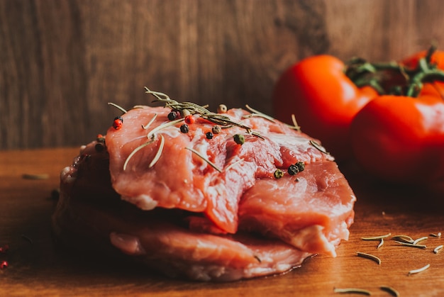 Pezzi di bistecca di maiale cruda con spezie ed erbe rosmarino, timo, basilico, sale e pepe