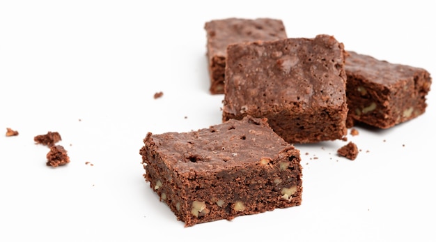 Pezzi di brownie al cioccolato al forno con noci isolati su sfondo bianco, delizioso dessert