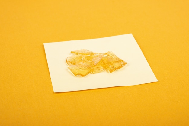 Pezzi di cera ad alto contenuto di THC su sfondo giallo, concentrato di fumo di marijuana.