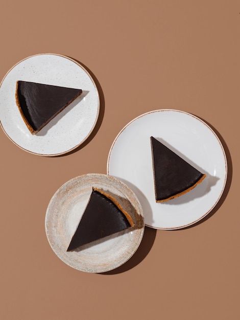 Pezzi di cheesecake al cioccolato fondente su sfondo beige e marrone, fotografia di cibo minimalista