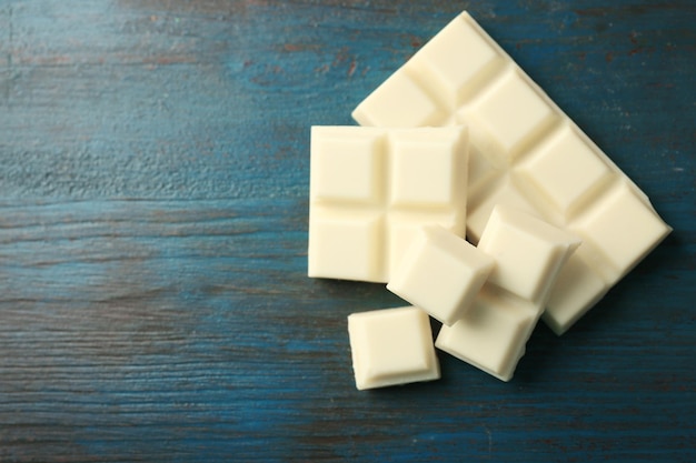 Pezzi di cioccolato bianco su fondo di legno di colore