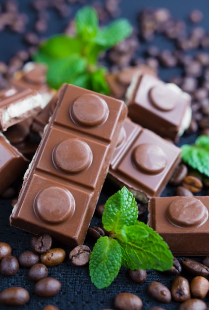 Pezzi di cioccolato con foglie di menta su sfondo nero