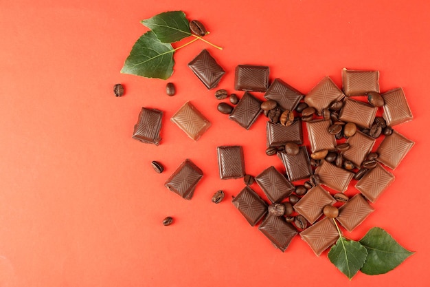 Pezzi di cioccolato con foglie verdi su sfondo rosso