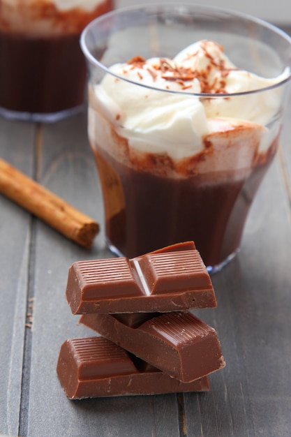 Pezzi di cioccolato con il milkshake al cioccolato e bastone di cannella su fondo di legno