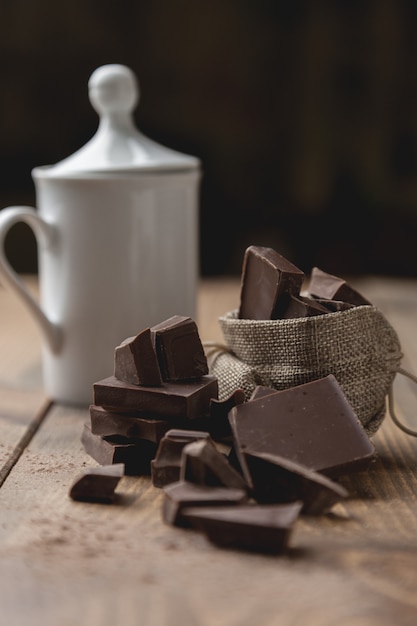 Pezzi di cioccolato fondente in una bustina accanto a una tazza