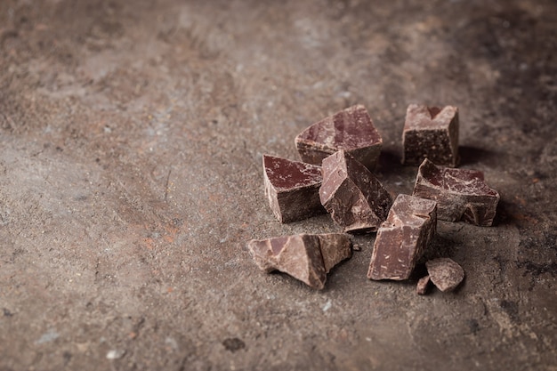 Pezzi di cioccolato fondente schiacciati su uno sfondo scuro, vista dall'alto