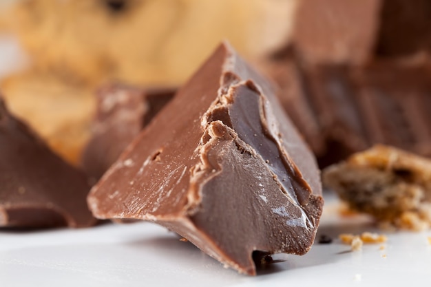 Pezzi di cioccolato molto dolci sul tavolo, cioccolato spezzato e biscotti di grano con gocce di cioccolato, prodotti da fast food, cibo al cacao molto calorico