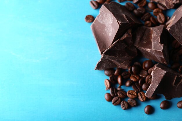 Pezzi di cioccolato nero e chicchi di caffè su fondo di legno colorato