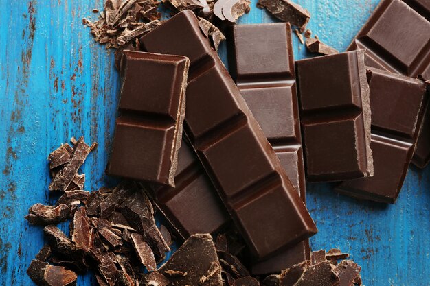 Pezzi di cioccolato nero su sfondo di legno colorato