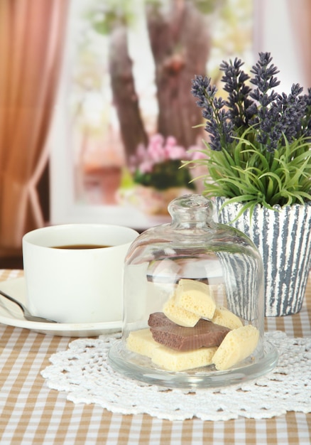 Pezzi di cioccolato sotto copertura di vetro e bevanda calda su sfondo luminoso