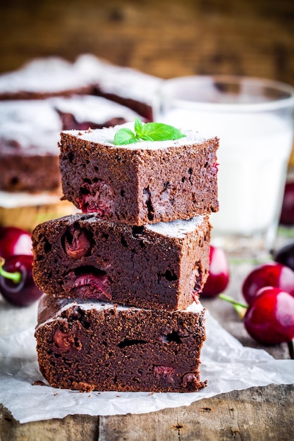 Pezzi di dolce fatto in casa di brownie al cioccolato con ciliegie e menta