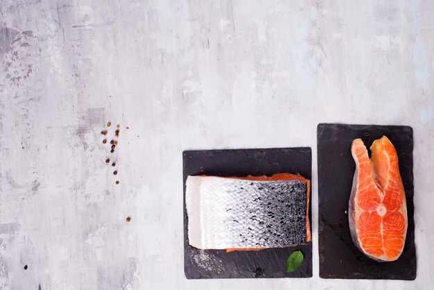 Pezzi di filetto di salmone su tagliere di ardesia scuro. Proteine magre.