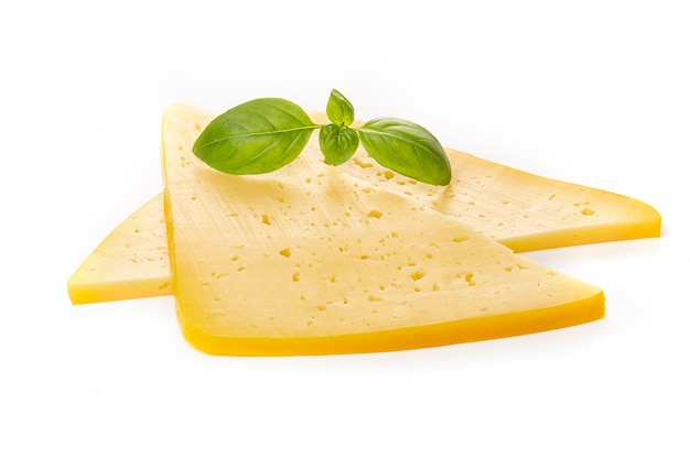 Pezzi di formaggio giallo semiduro o duro con fori e foglia di basilico isolati su sfondo bianco.