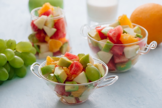 Pezzi di frutta tropicale in un bicchiere. Arancia affettata, mela, fette di anguria in ciotola di vetro. Agrumi