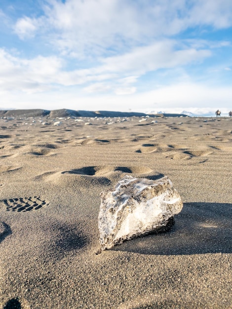 Pezzi di ghiaccio brillano come diamanti a forma di cuore sulla spiaggia di sabbia nera in Islanda sotto il cielo blu nuvoloso