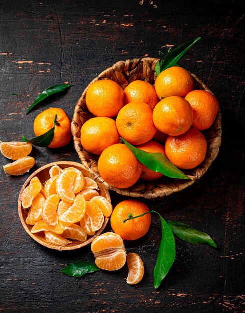 Pezzi di mandarini freschi su un piatto con foglie