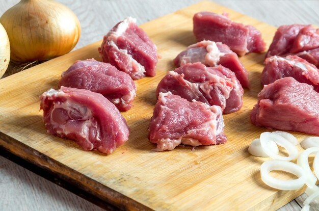 Pezzi di manzo crudo e anelli di cipolla sul taglio del cinghiale