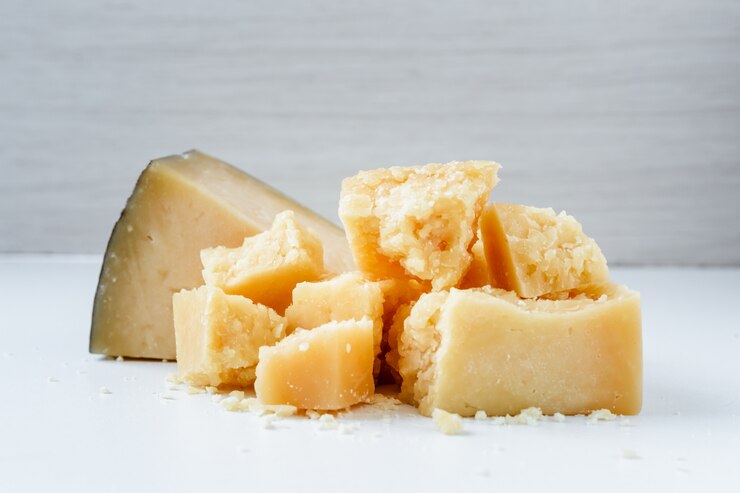 Pezzi di parmigiano accatastati in un mucchio su uno sfondo bianco