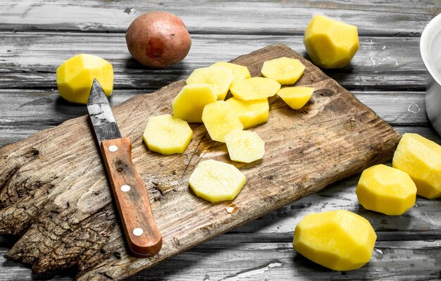 Pezzi di patate fresche su un tagliere con un coltello