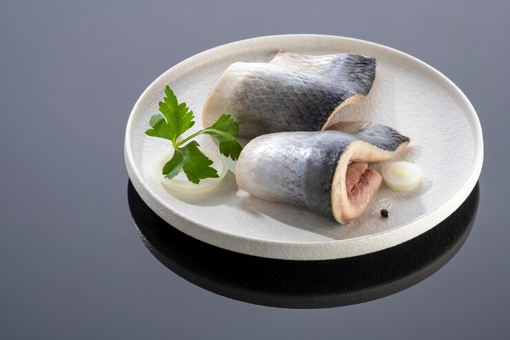 Pezzi di pesce aringa salato su un piatto bianco su uno sfondo a specchio