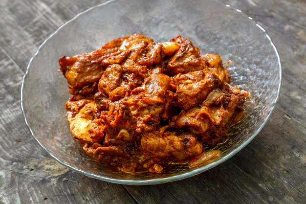 Pezzi di pollo in salsa fritti in una lastra di vetro su un tavolo di legno scuro