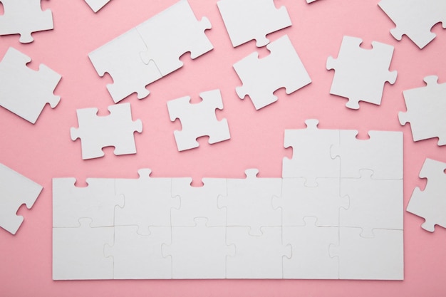 Pezzi di puzzle bianchi incompiuti su sfondo rosa