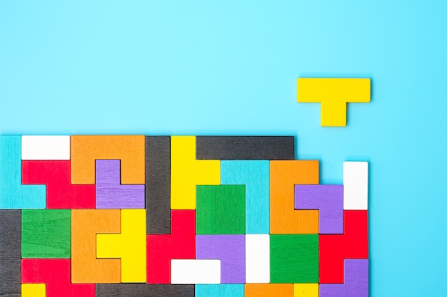 Pezzi di puzzle in legno colorato su sfondo blu, blocco di forma geometrica. Concetti di pensiero logico, enigma, soluzioni, razionale, strategia, giornata mondiale della logica e istruzione