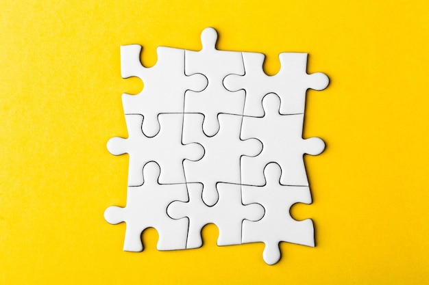 Pezzi di puzzle vuoti collegati su uno sfondo giallo