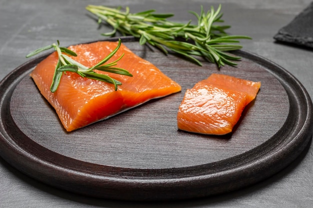 Pezzi di salmone e rametti di rosmarino sul tagliere