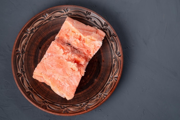 Pezzi di salmone pressati congelati su un piatto su sfondo grigio