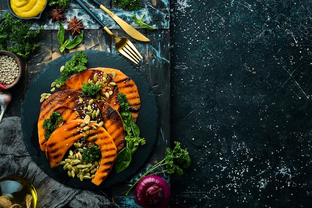 Pezzi di zucca al forno con semi di zucca in una lastra di pietra nera Menu autunnale Dieta Vista dall'alto Spazio libero per il testo