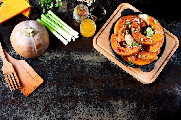 Pezzi di zucca cotti in una padella con verdure e semi. Zucca Al Forno. Pranzo vegano con zucca speziata al forno. Utile spuntino autunnale. Pranzo di Halloween