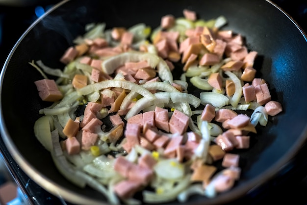 Pezzi fritti di salsicce e cipolla in padella. cena cucina da vicino