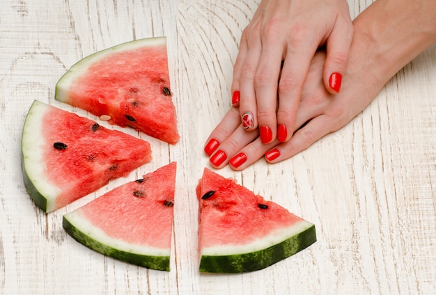 Pezzi triangolari di anguria e mani di donna con una manicure