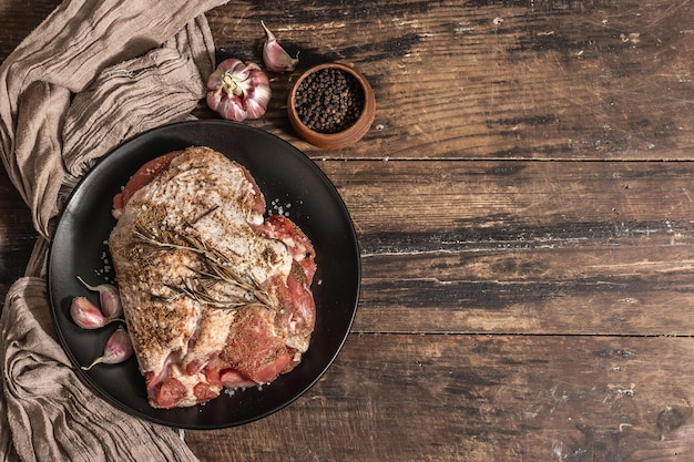 Pezzo di carne cruda di tacchino marinato con spezie. Un ingrediente utile per preparare cibi sani. Una luce dura moderna, ombra scura, stile rustico. Tavolo in legno vintage, vista dall'alto