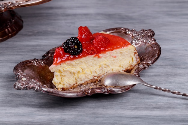 Pezzo di cheesecake con frutta sulla cucina in metallo