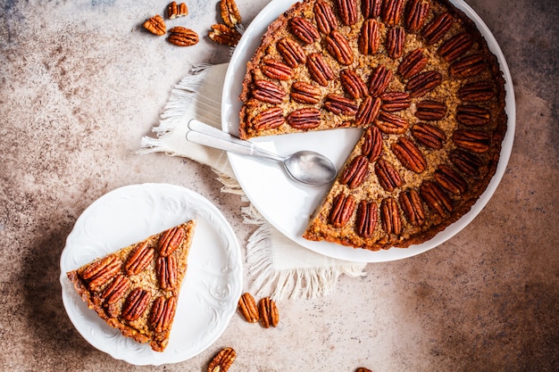 Pezzo di crostata di noci di pecan su fondo grigio-marrone. Concetto di dessert vegan.