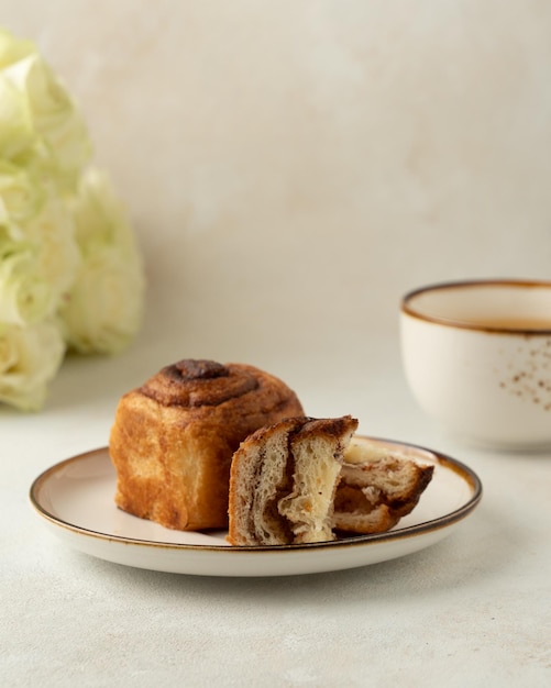 Pezzo di cruffin e tazza di rose bianche da tè