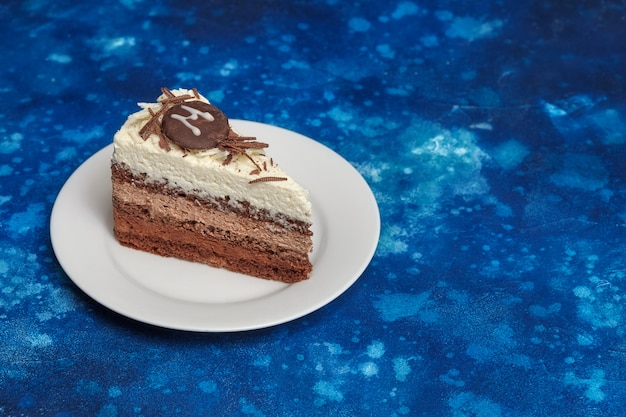 Pezzo di deliziosa torta di mousse con tre diversi tipi di cioccolato sul piatto bianco