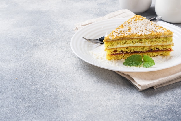 Pezzo di deliziosa torta sfoglia con crema al burro e marmellata di frutti di bosco su un piatto con la menta.