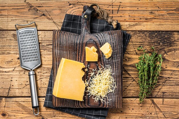 Pezzo di formaggio cheddar grattugiato su una tavola di legno. Fondo in legno. Vista dall'alto.