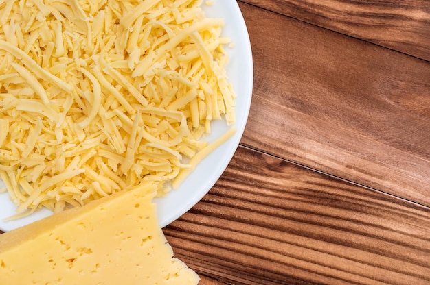 Pezzo di formaggio e piatto con formaggio grattugiato sul tavolo Vista dall'alto Copia spazio