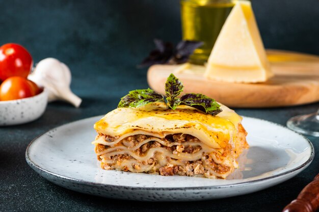 Pezzo di gustose lasagne calde su sfondo chiaro. Lasagne italiane tradizionali. Cibo italiano. Lasagne da vicino. Ragù alla bolognese. Besciamella. Natura morta di cibo. Lasagne di carne fatte in casa.